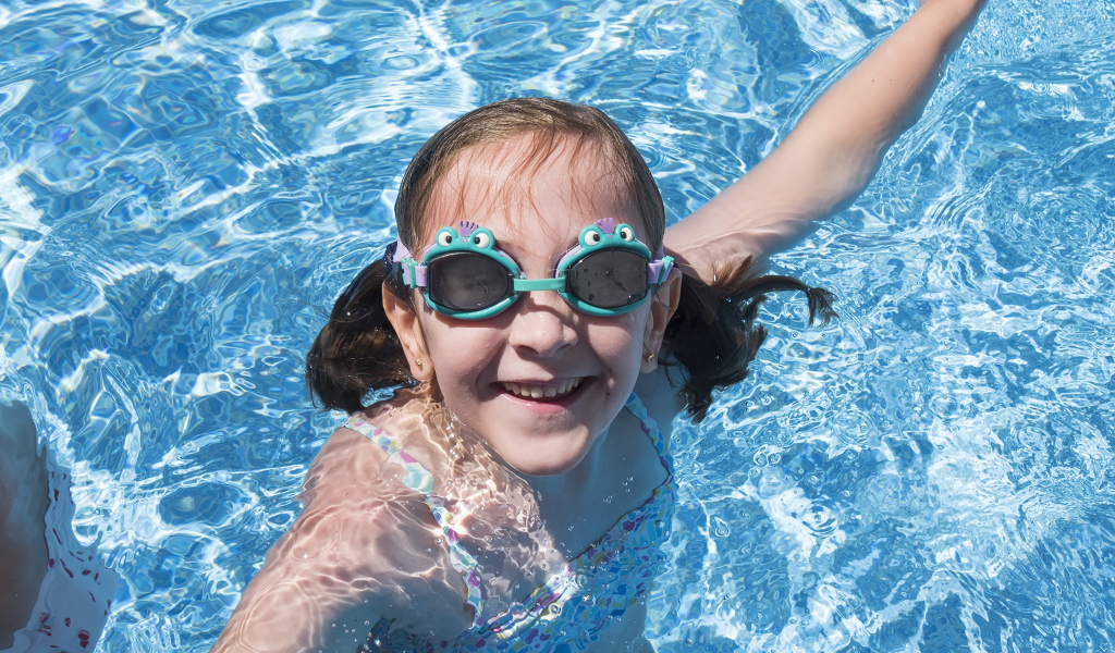 Маленькая улыбающаяся девочка в очках в бассейне 
