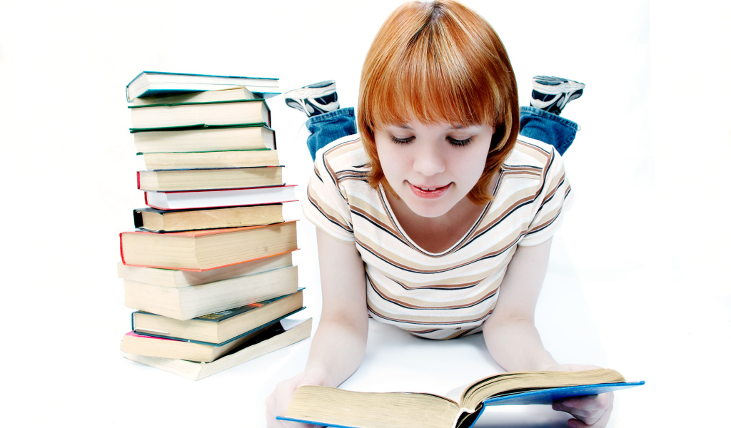 Рыжеволосая девочка школьница читает книги на белом фоне 