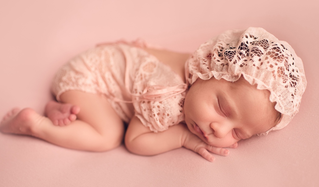 Спящий грудной ребенок в розовом костюме 