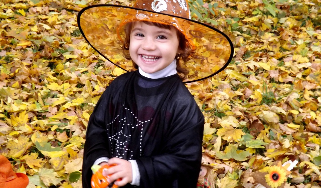 Улыбающаяся девочка в костюме ведьмы на Хэллоуин