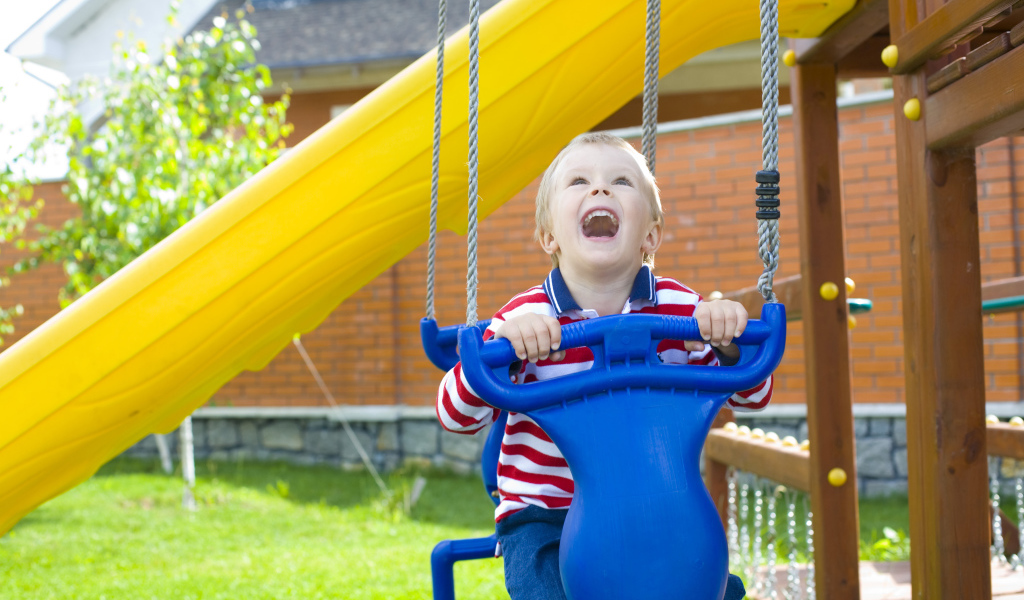 Улыбающийся ребенок на качели 