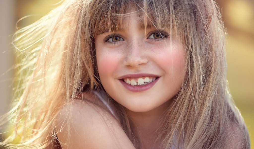 Улыбающаяся девочка с веснушками на лице 