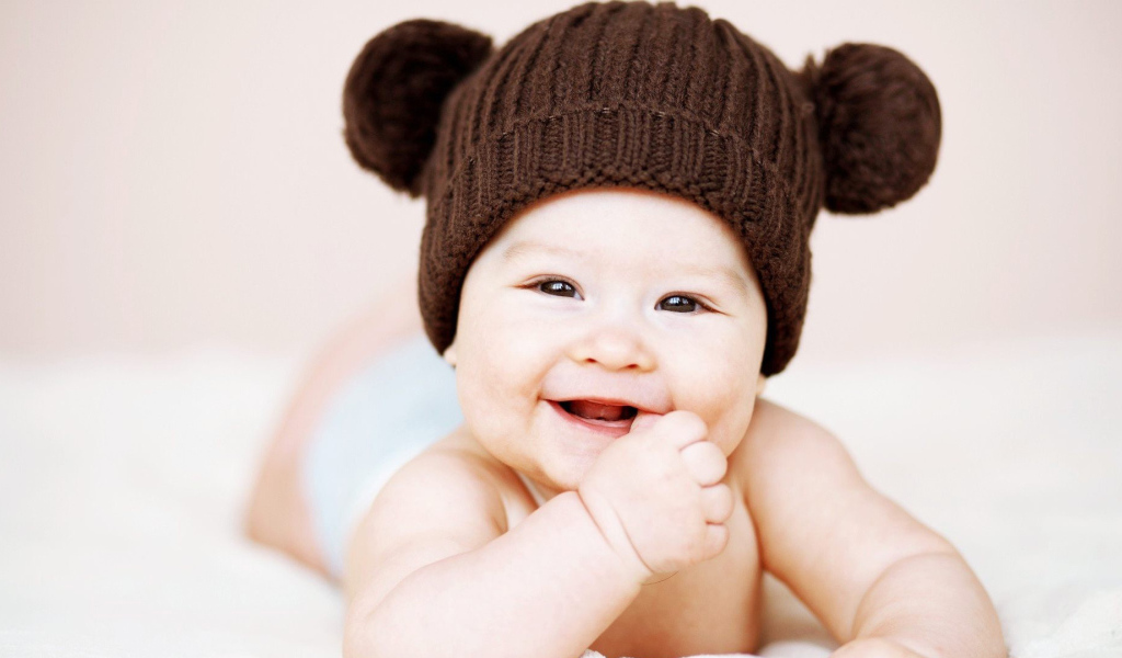 Улыбающийся грудной ребенок в коричневой шапке