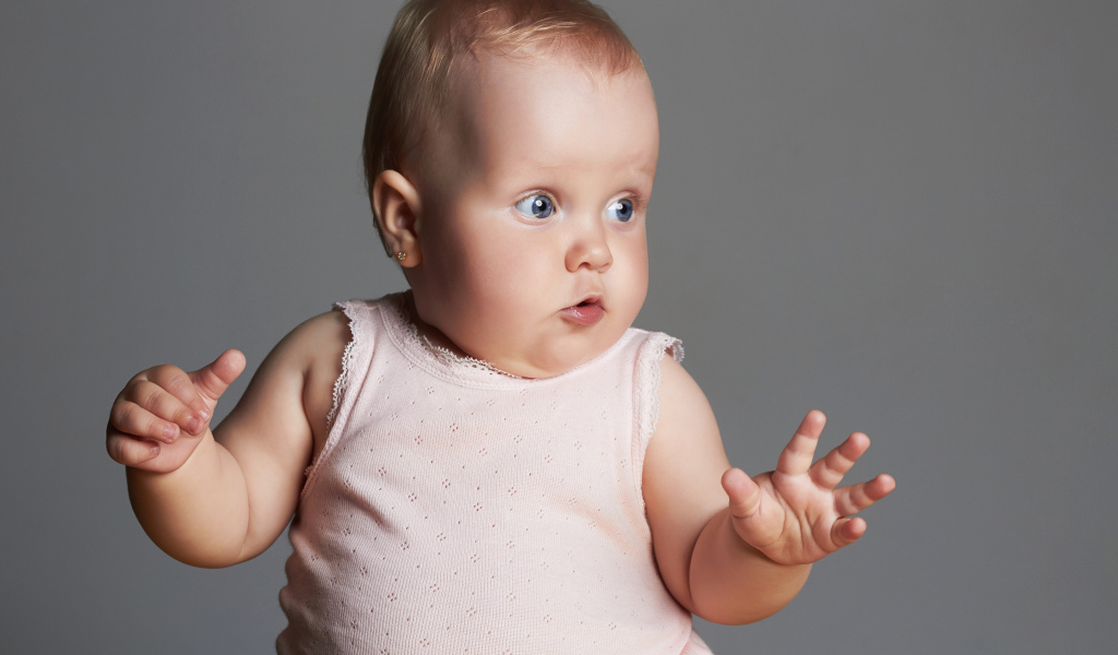 Удивленный маленький ребенок на сером фоне