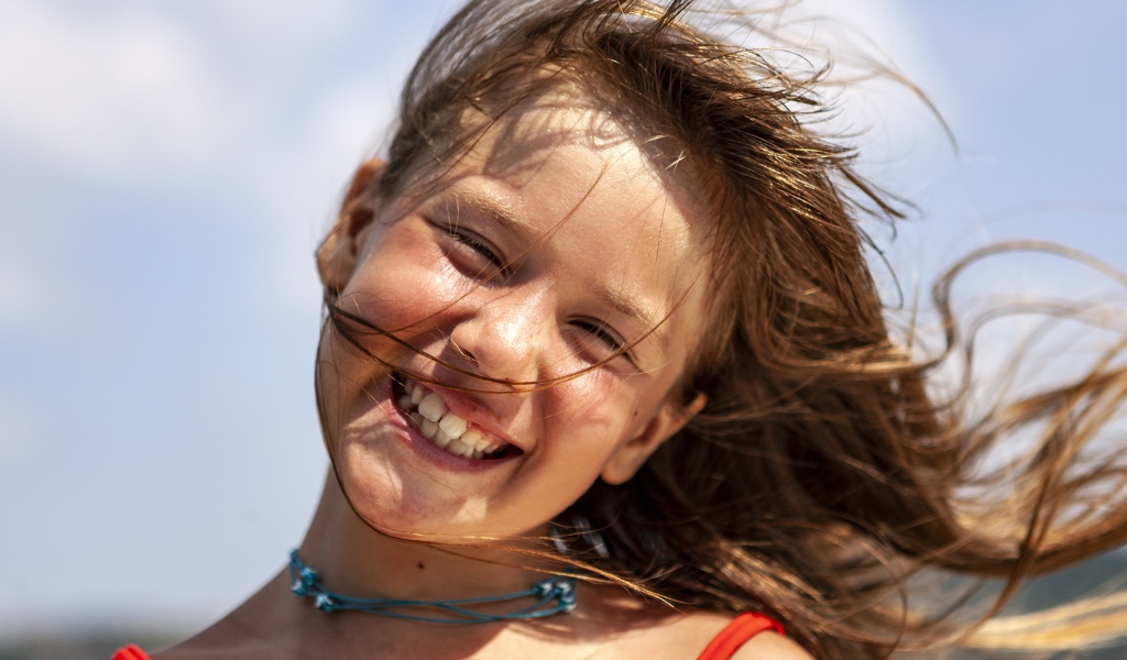 Ветер развивает волосы улыбающейся девочки