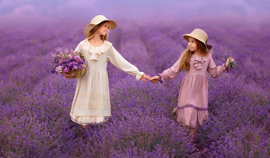 Две маленькие девочки идут по лавандовому полю 