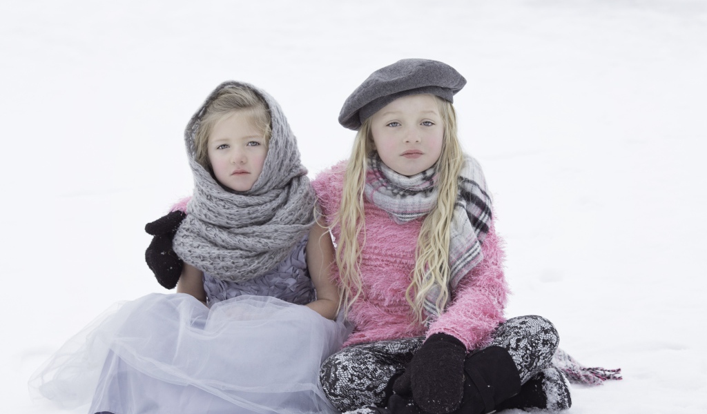 Две маленьких сестры сидят на снегу 