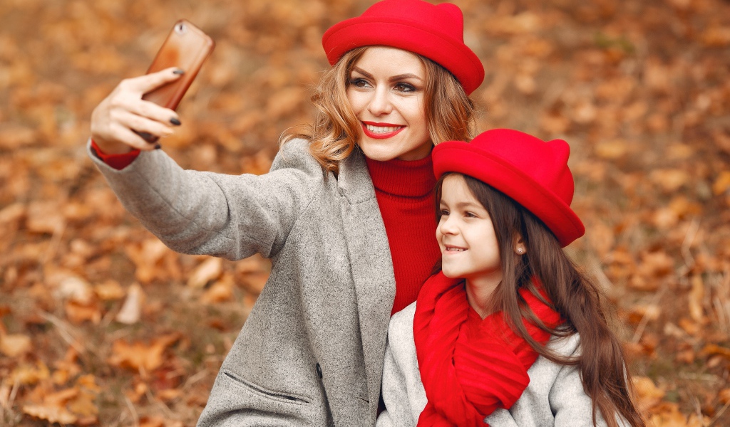 Женщина с маленькой девочкой делают селфи в лесу 