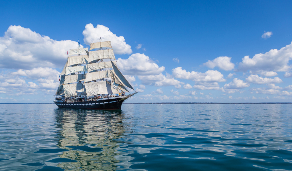 Большой парусный барк в небе над морем с белыми облаками 