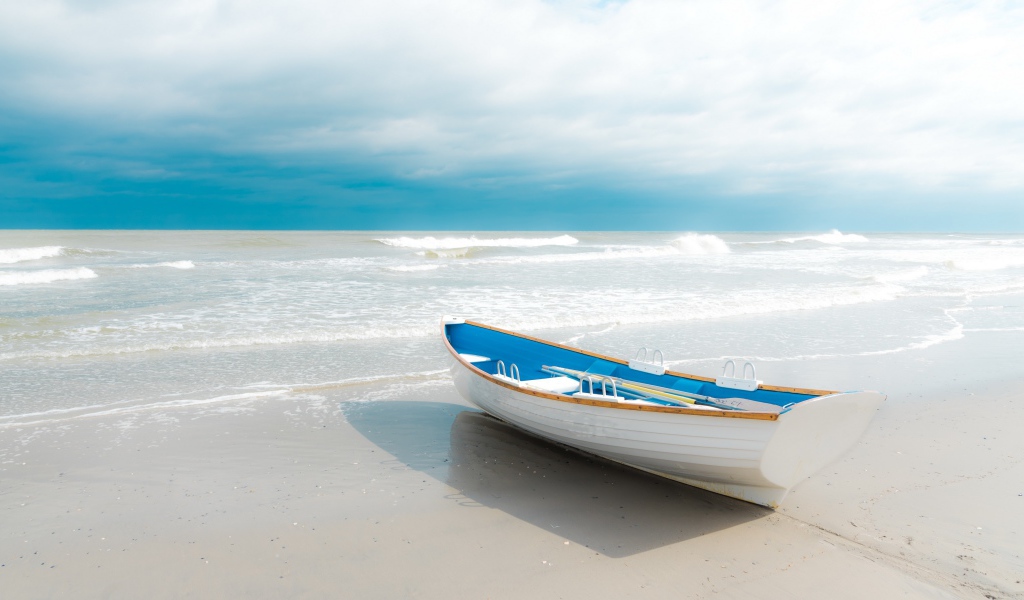 The boat stands on white sand by the sea
