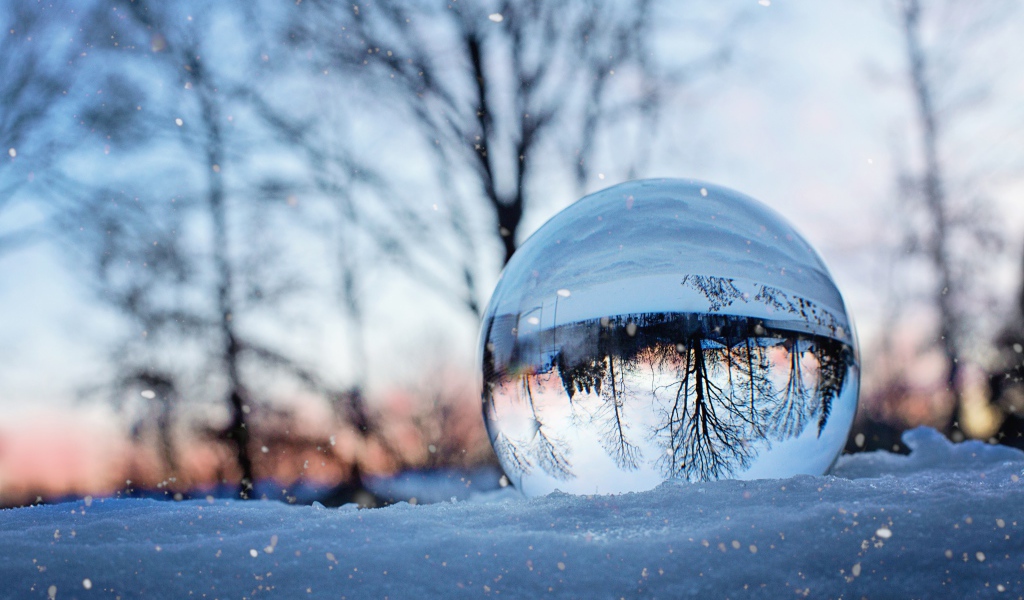 Большой стеклянный шар лежит на холодном снегу