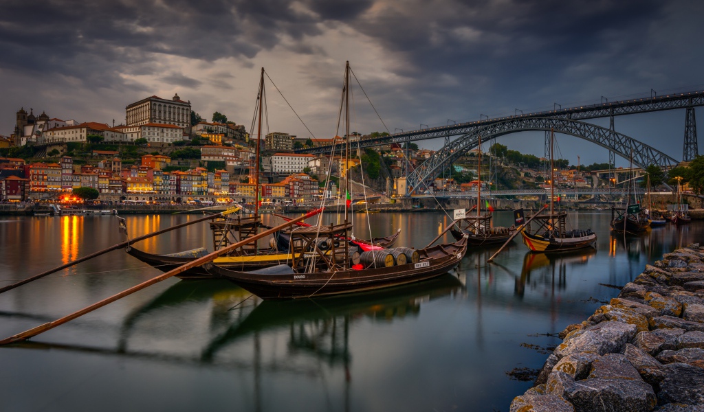 Лодки в порту на фоне моста и города на закате 