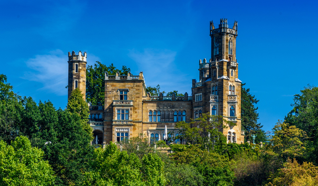 Старинный замок в зарослях деревьев на фоне голубого неба, Германия