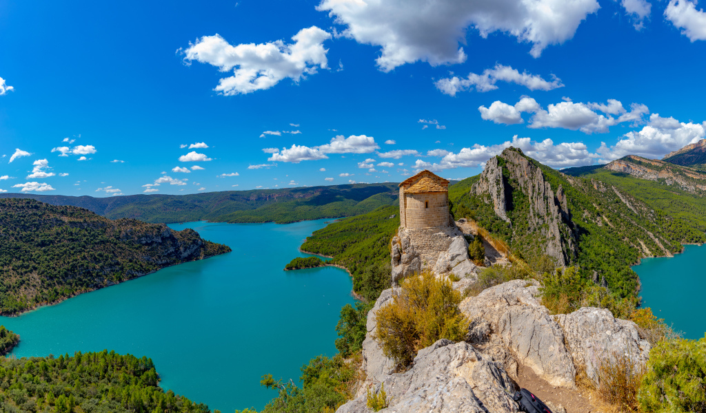 Старое здание на вершине утеса на фоне реки под голубым небом, Испания 