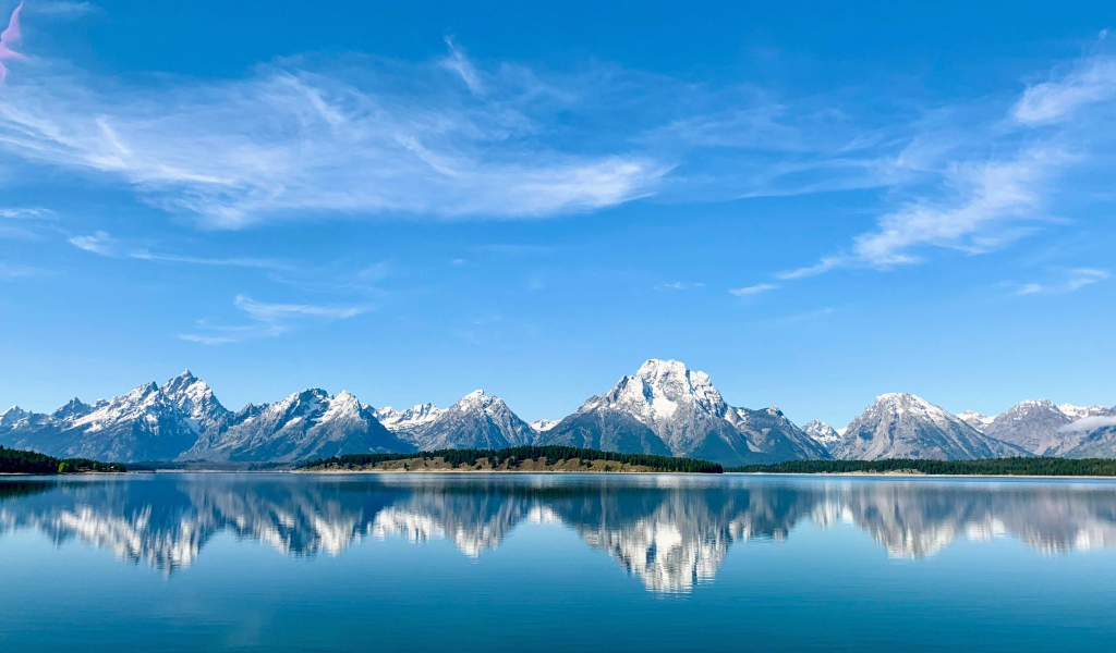 Вид на заснеженные горы под голубым небом у озера, Национальный парк Гранд Титон, Вайоминг. США