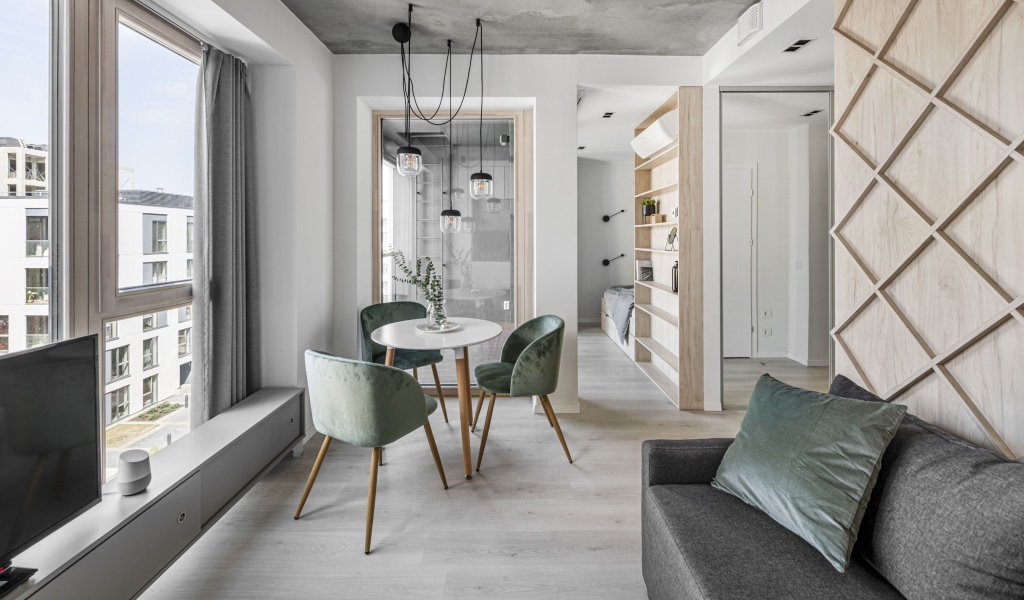 Стол  с креслами стоит у большого окна в квартире 