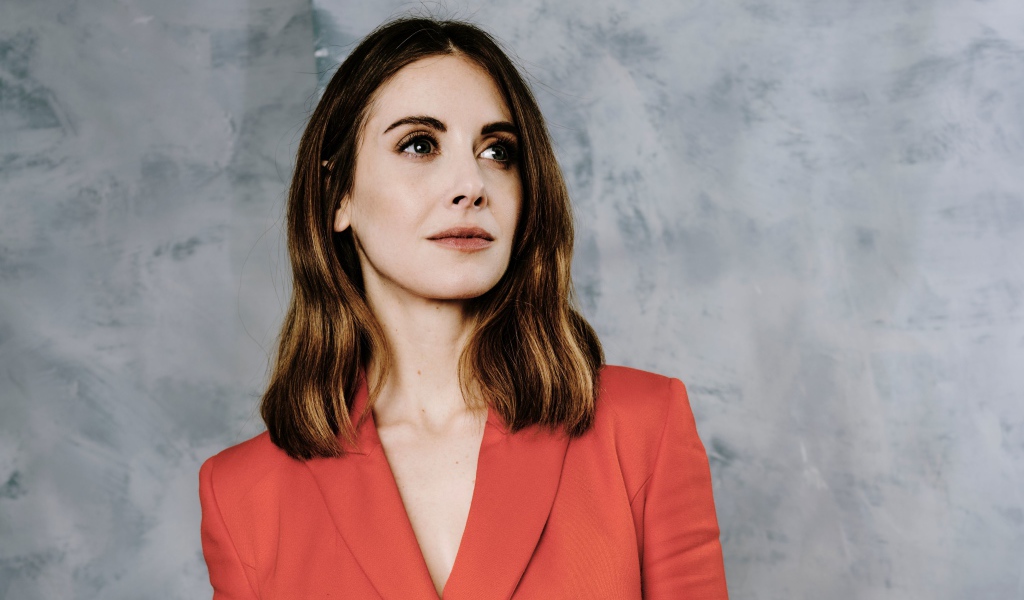 Актриса Элисон Бри в красном пиджаке на сером фоне