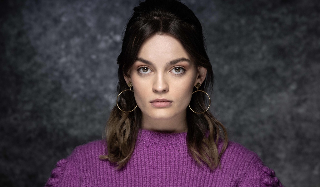 Актриса Эмма Маккей в сиреневом свитере на сером фоне