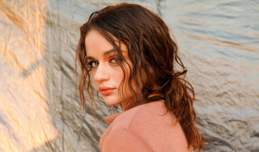 Актриса Джои Кинг стоит боком у стены 