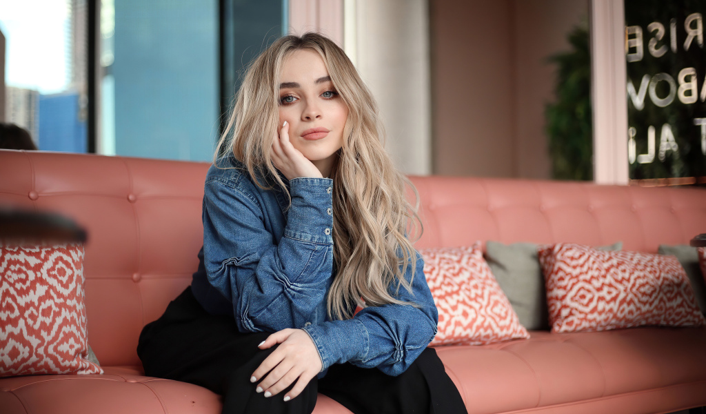 Актриса Сабрина Карпентер сидит на диване в комнате