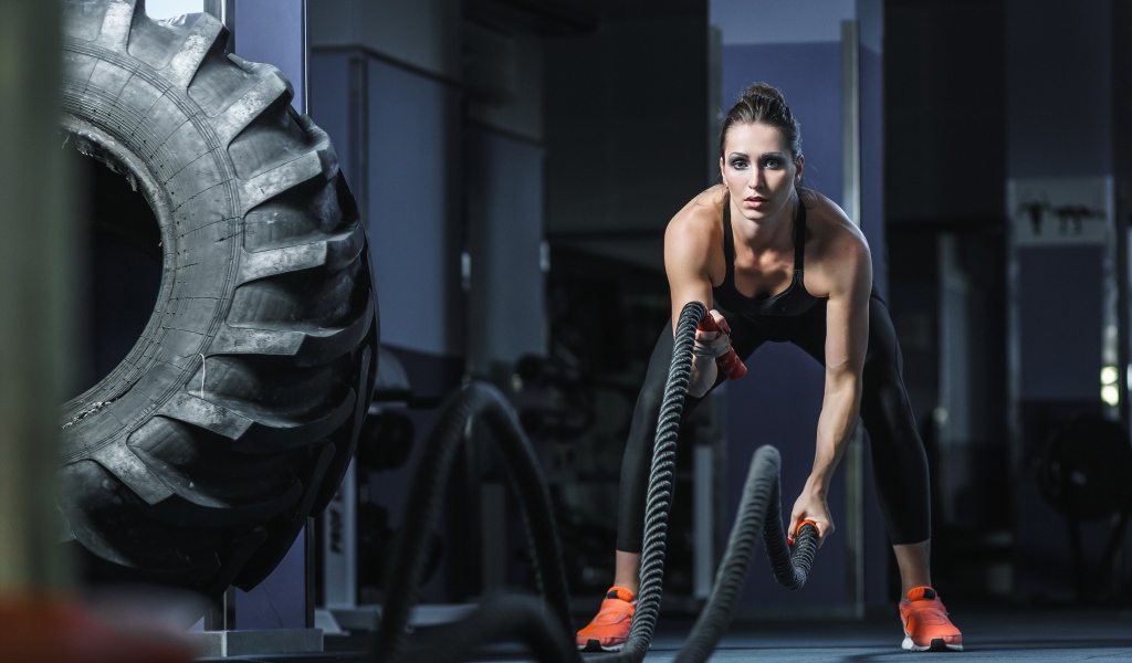 Спортивная девушка занимается с канатами в спортзале 