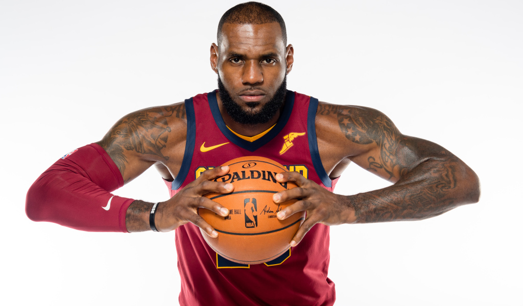 Баскетболист Леброн Джеймс с мячом в руках на сером фоне