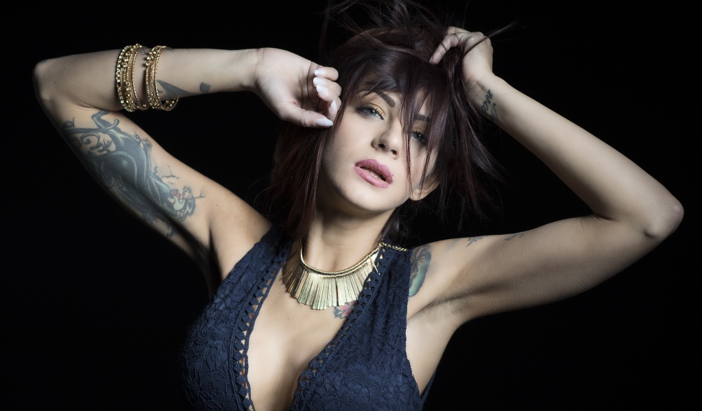 Красивая девушка в черном платье с татуировками на теле 
