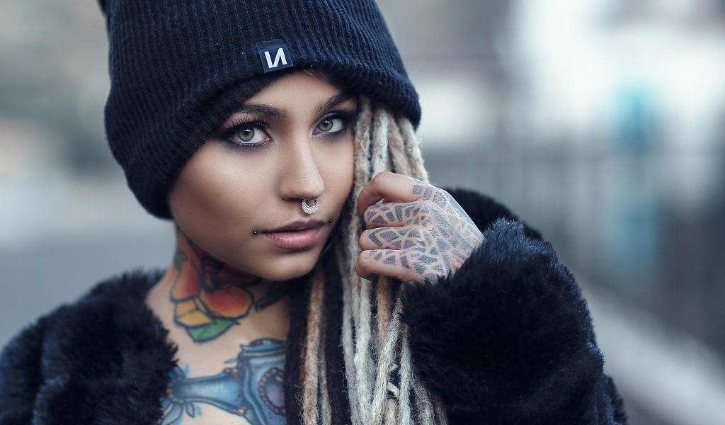 Beautiful girl in a black hat with tattoos on her body