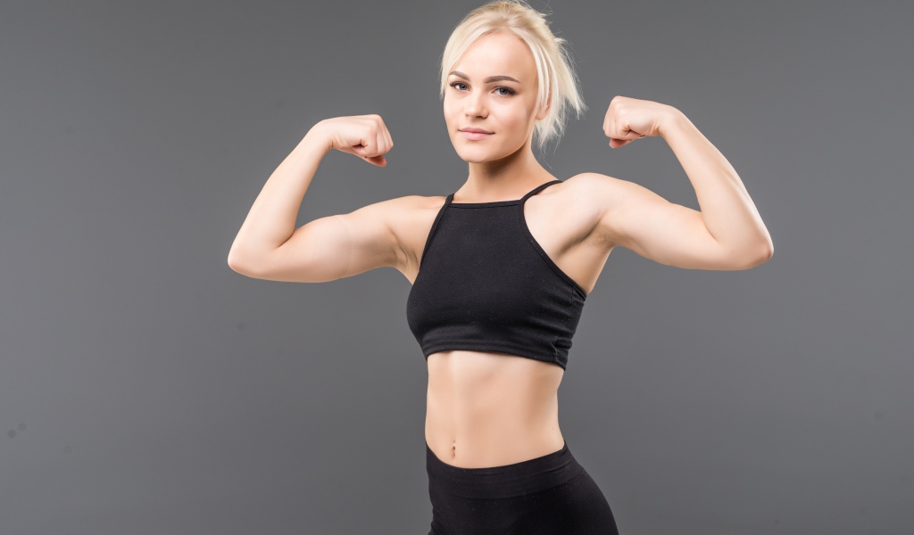 Красивая стройная спортивная девушка показывает мускулы