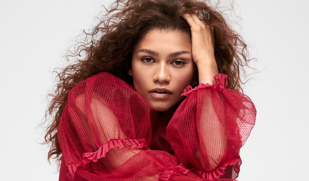 Кареглазая актриса Зендая в красном наряде с рукой в волосах