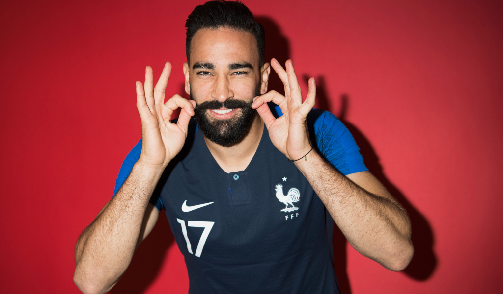 Французский футболист Адиль Рами на красном фоне