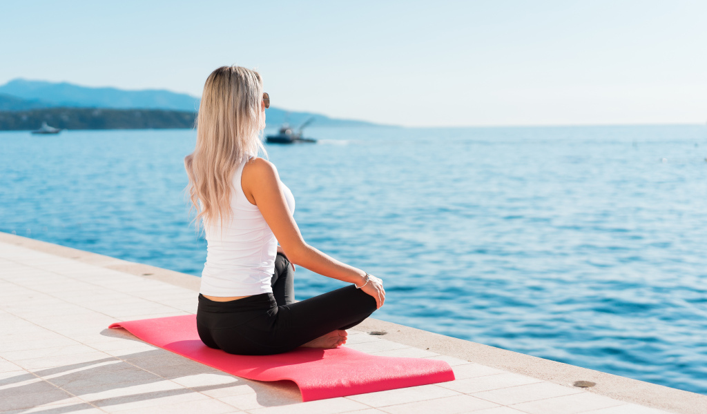 Девушка медитирует на берегу моря 