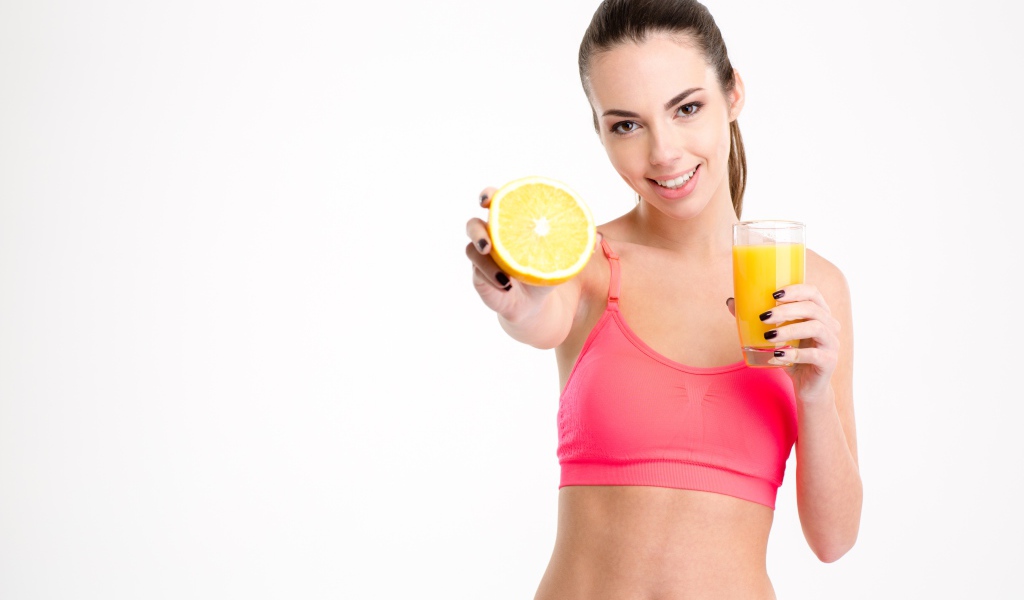 Девушка со стаканом сока и апельсином на белом фоне