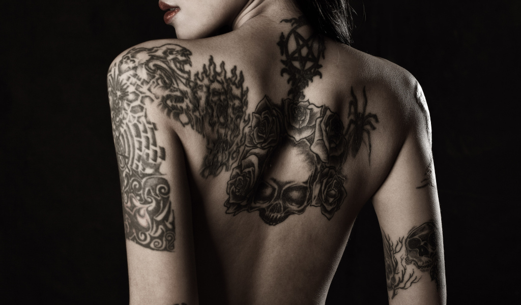 Девушка с татуировками на руках и спине