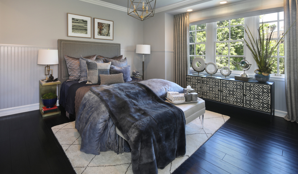 Большая кровать с мягким серым покрывалом в спальне 