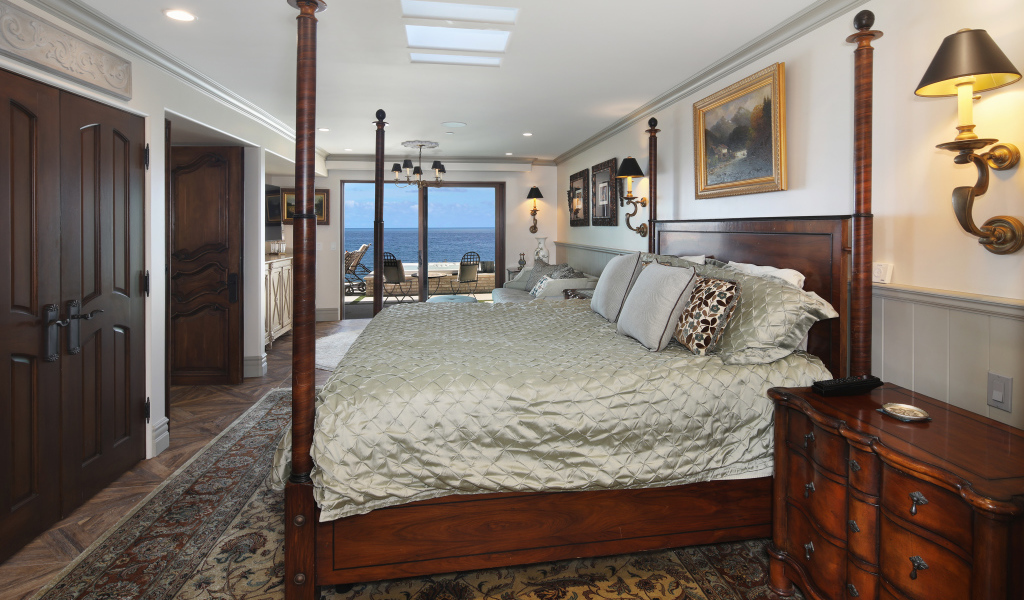 Большая деревянная кровать в спальне с видом на море 