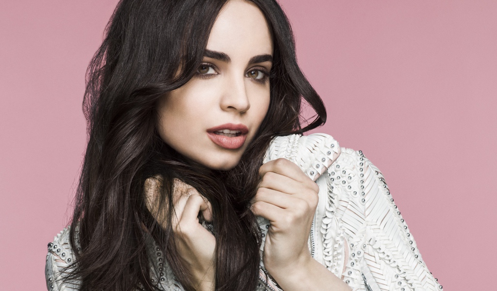 Длинноволосая актриса София Карсон на розовом фоне