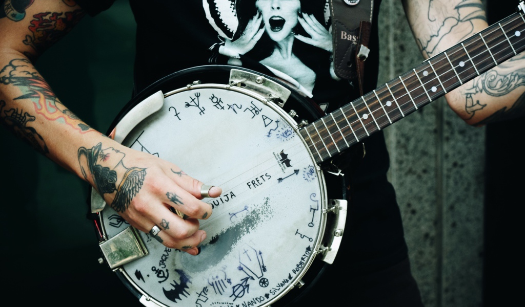 Мужчина с татуировками на руках с гитарой