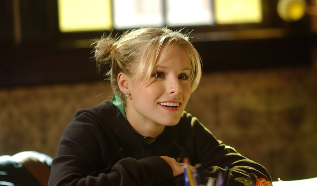 Улыбающаяся актриса Кристен Белл сидит в классе 