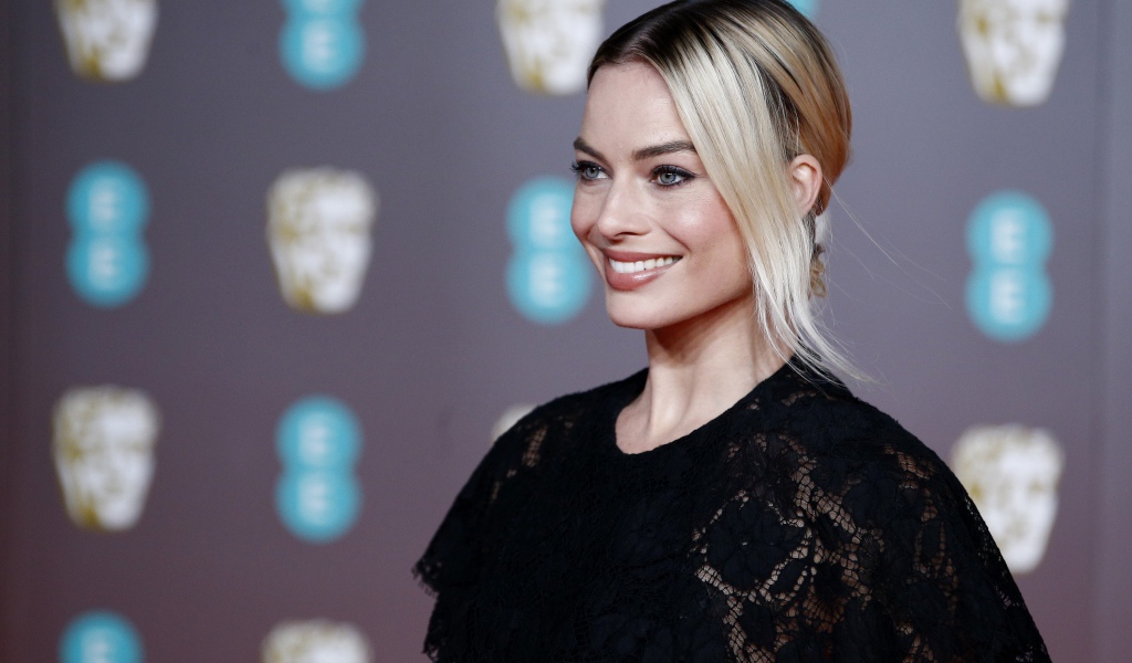 Улыбающаяся актриса Марго Робби в черном платье 