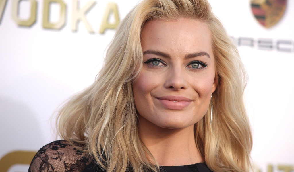 Улыбающаяся блондинка, актриса Марго Робби у стены