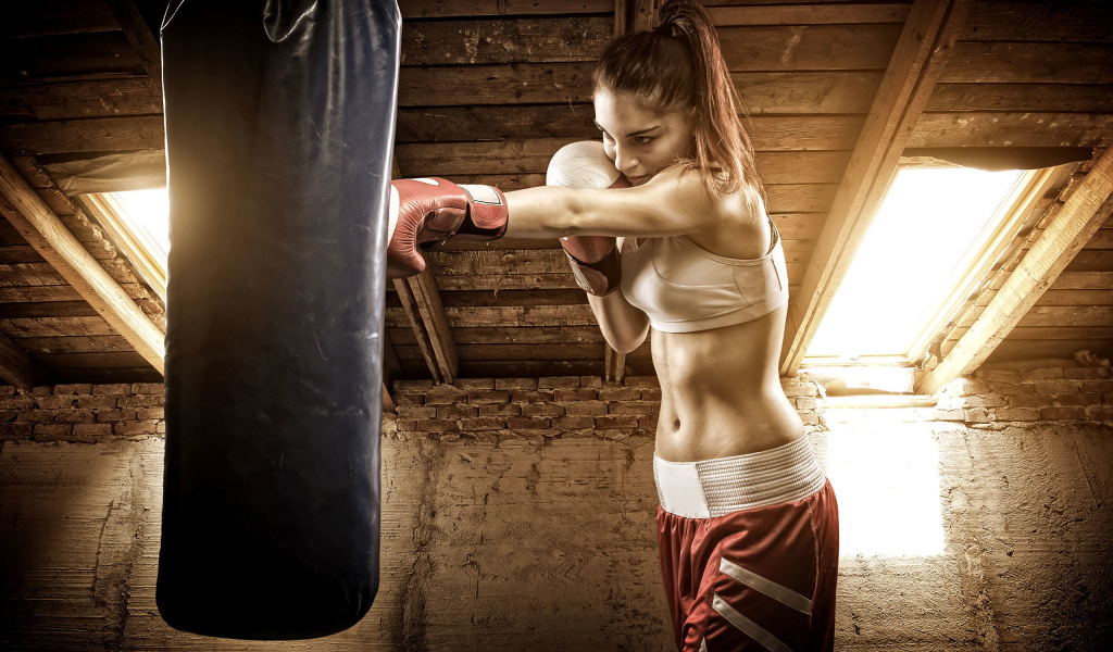 Спортивная девушка бьет боксерскую грушу 