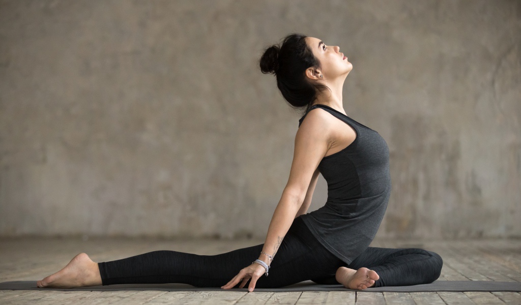 Спортивная девушка делает растяжку на полу 