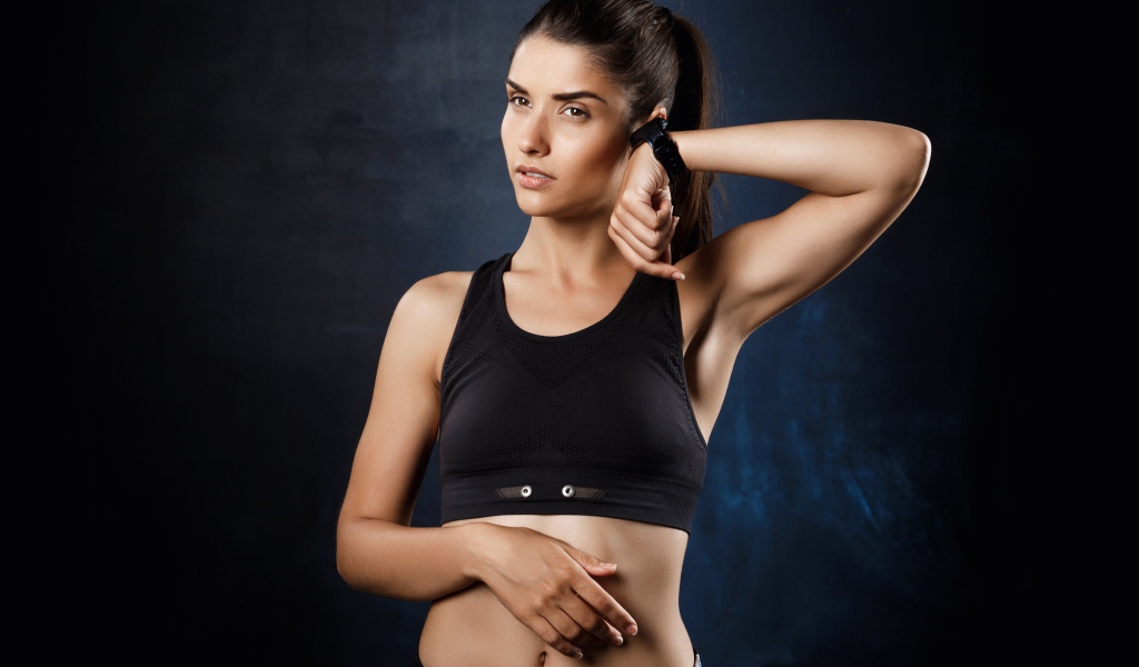 Спортивная девушка в черном костюме с часами на руке