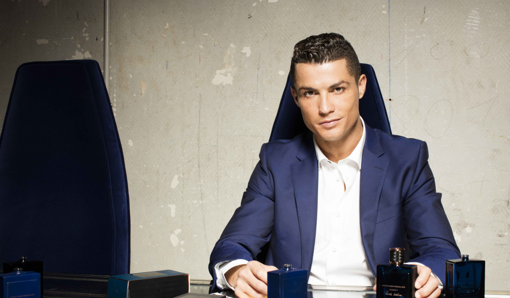 Стильный мужчина, футболист Криштиану Роналду с духами за столом