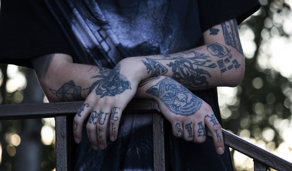 Татуировки на руках у парня в черной футболке 
