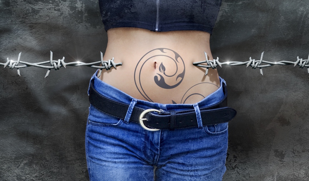 The belly of a young girl with a tattoo is pierced with barbed wire