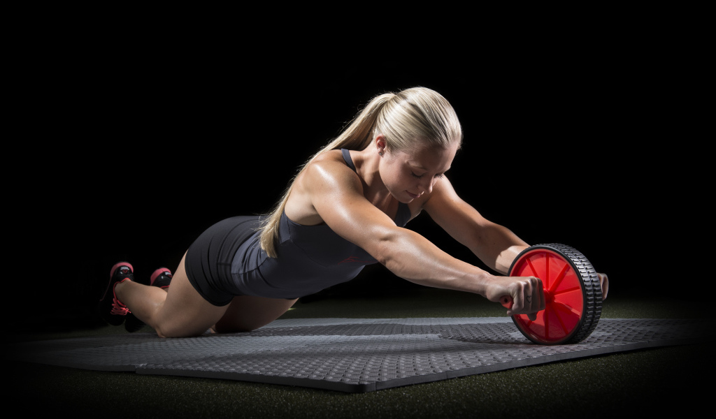 Девушка занимается фитнесом с колесом