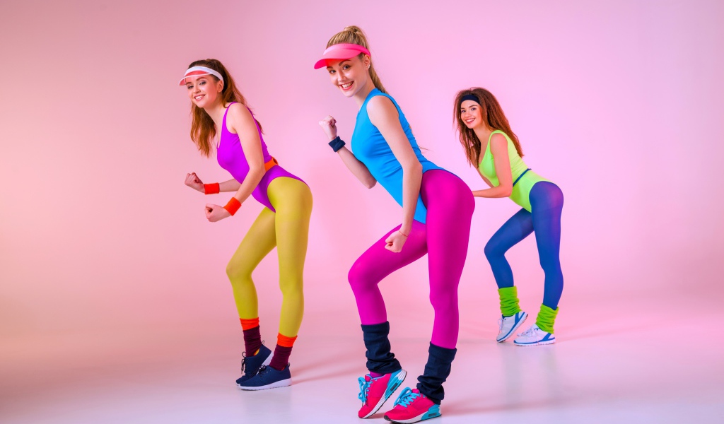 Три девушки занимаются фитнесом на розовом фоне
