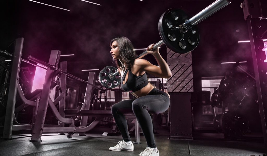 Weightlifter girl lifts the barbell in the gym